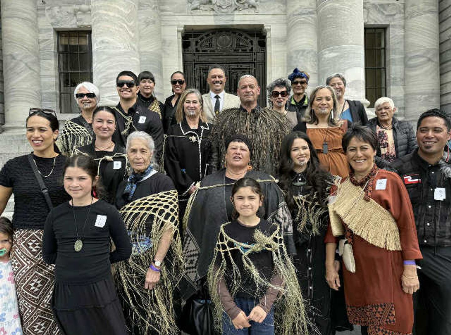 Arnold Gurau (2nd row from back, centre with cape) standing amongst his whanau on Parliament steps - the occasion is the 3rd and final reading of the Ngati Paoa Treaty settlement - 5 Nov 2025
