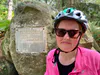 Cherie Jacobson in front of the commemorative plaque attached to a rock in the Fontainebleau Forest, 2025.