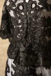 Detail of a black lace over-jacket displayed on a dress form