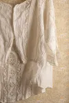 Detail of blouse hanging against floral-patterned wallpaper