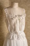 Detail of a white corset cover displayed on a dress form.