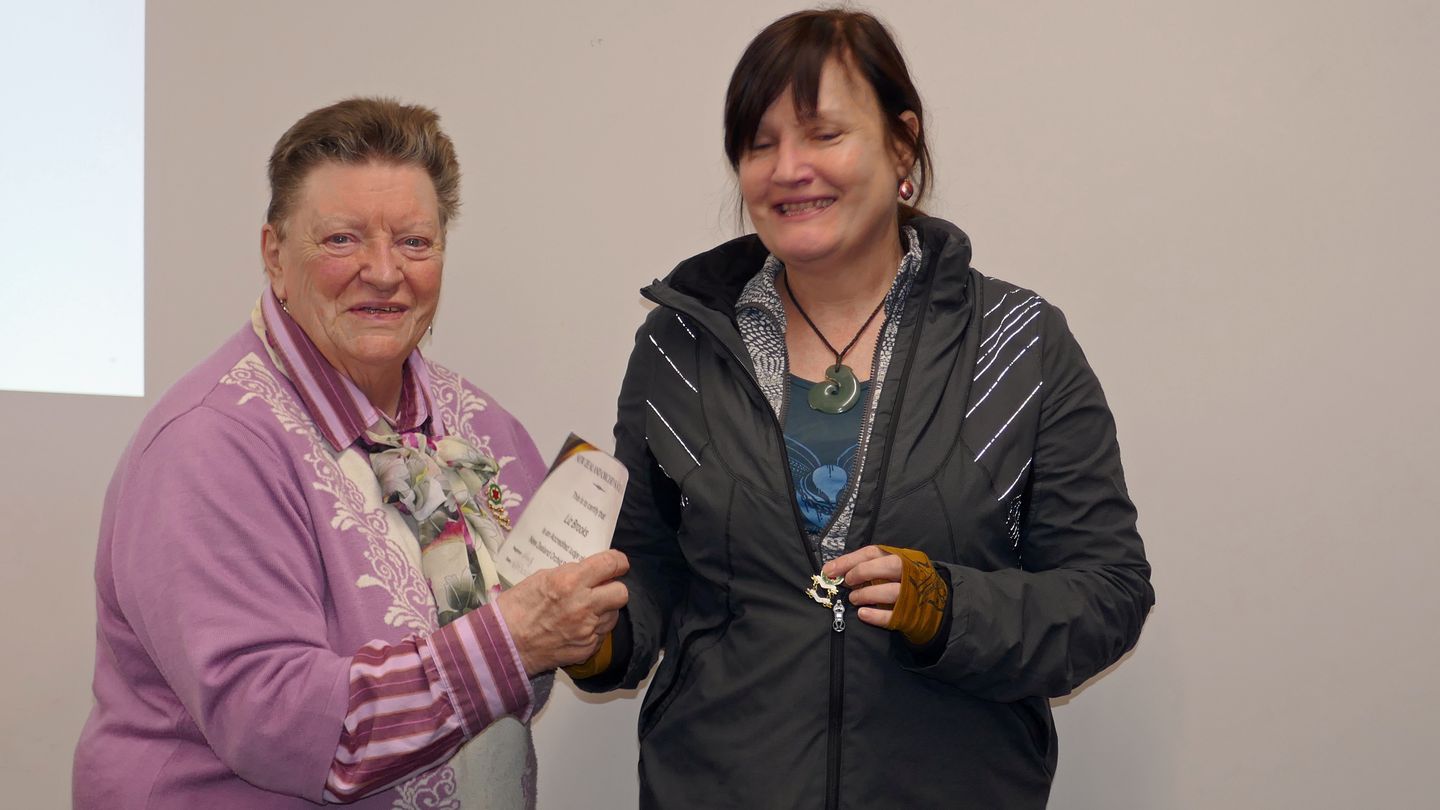 Liz proudly receiving their NZOS Judge’s Certificates and Badge from Leigh Leaity