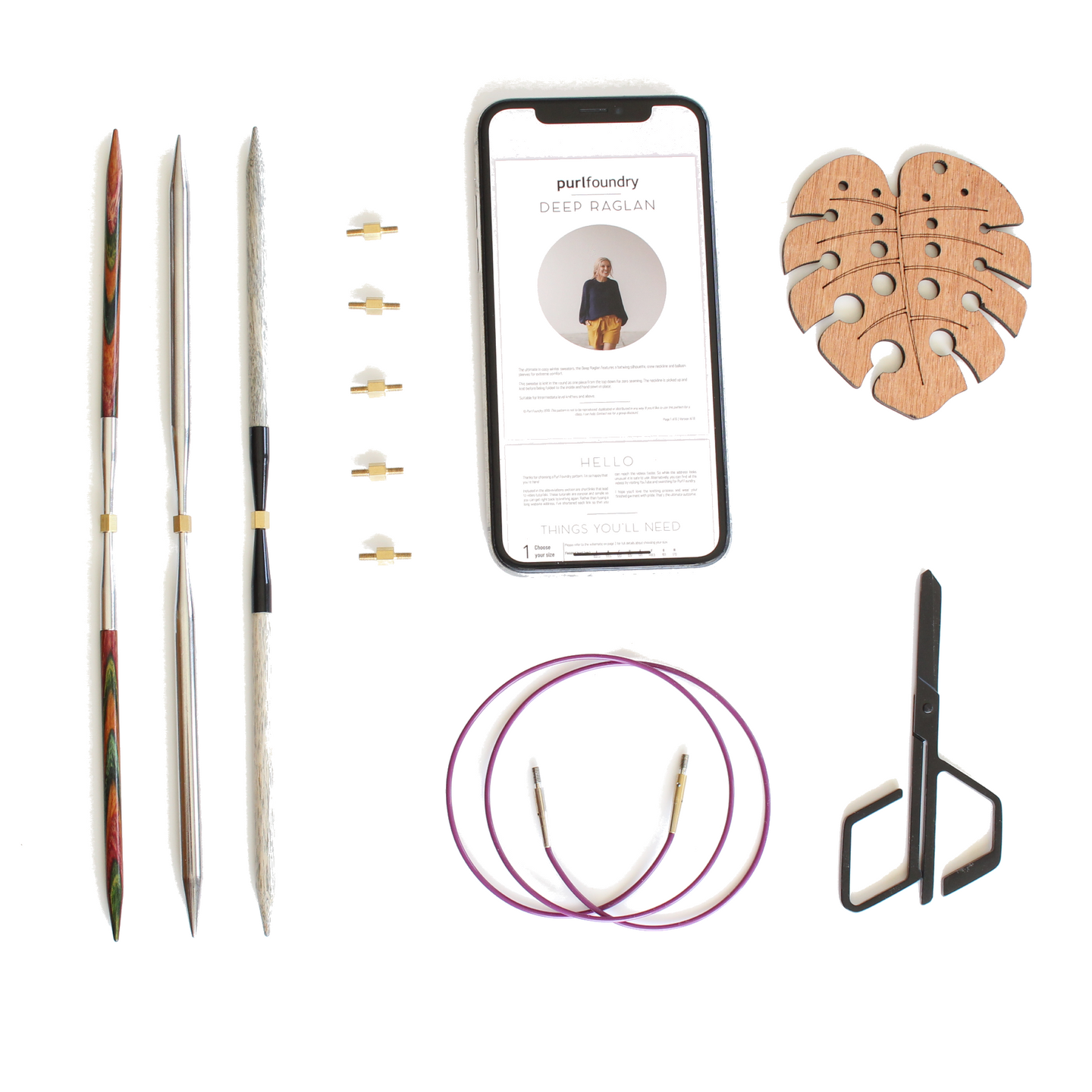A flatlay of knitting tools eg needle tips, scissors, needle gauge, cord and a PDF pattern on a mobile phone