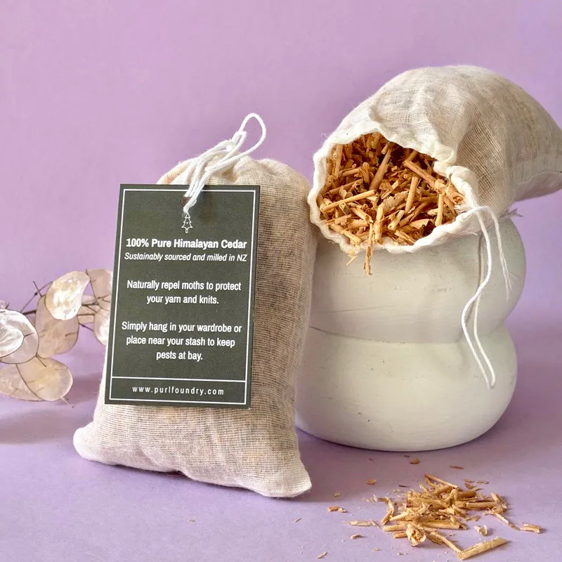 A bag stands next to an open pouch of cedar flakes. Some loose flakes lie beneath the open pouch