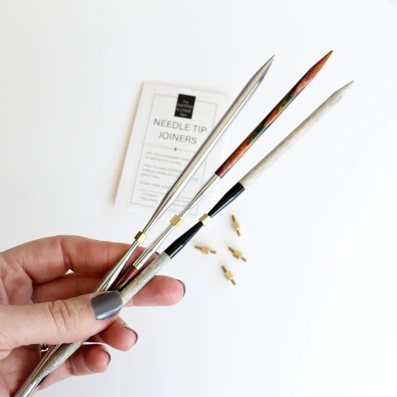 A hand holding three interchangeable knitting needle tips that are joined in the middle with a screw