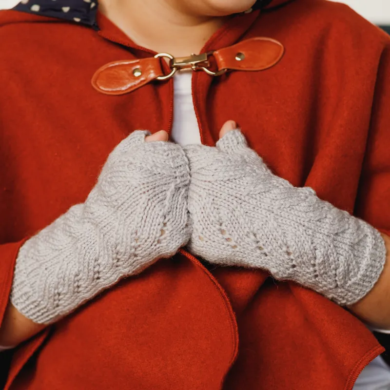 Child wearing a red cape and hand knit fingerless gloves