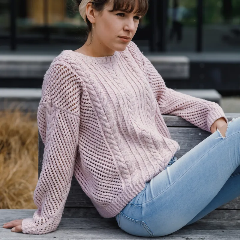 Woman wearing a pink hand knit sweater with mesh and cable stitches