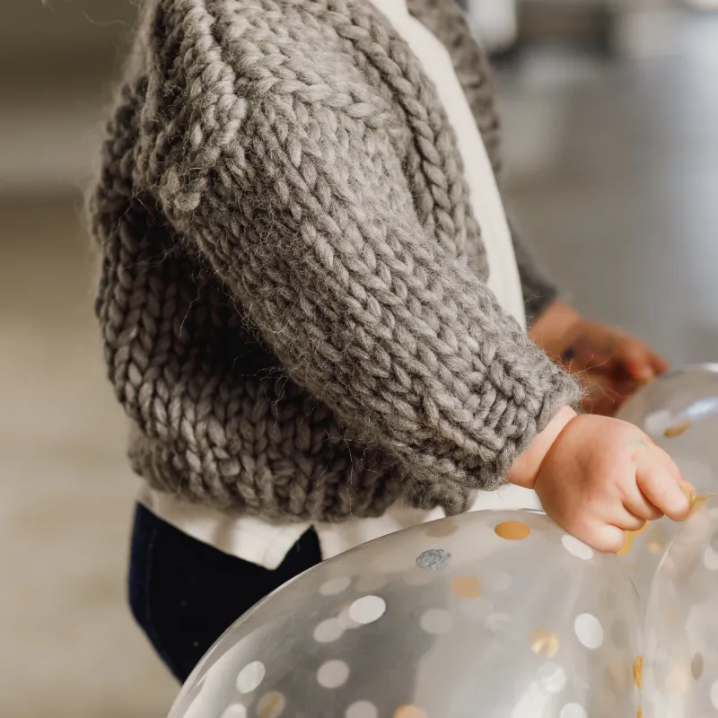 Sleeve of a grey, hand knitted cardigan for a toddler