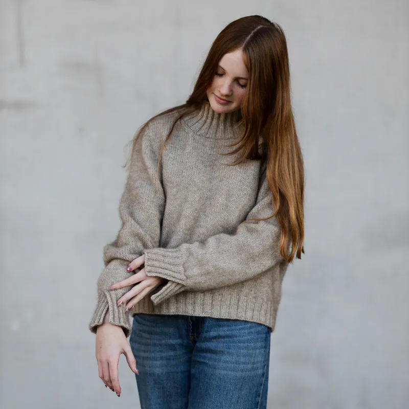 A woman looks down at the split, ribbed cuffs on her possum blend sweater.