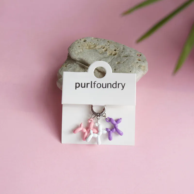 Purple, pink and white knit stitch markers in the shape of balloon animals