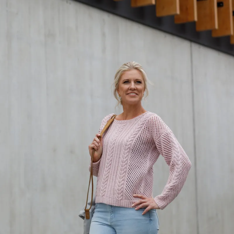 Woman wearing a pink sweater with mesh and cable stitches