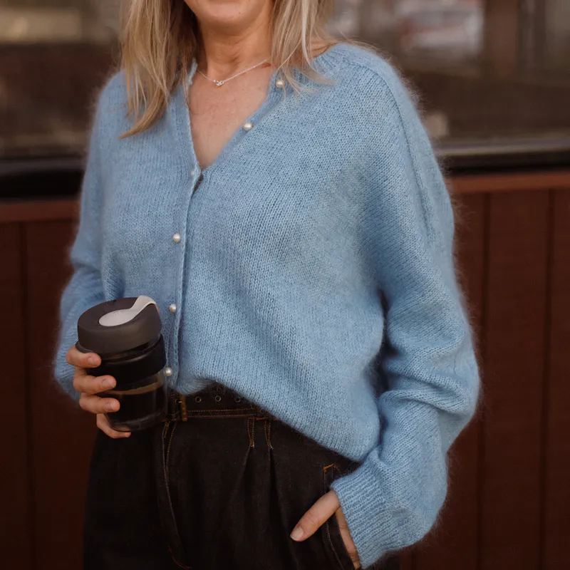 A woman holding a takeaway coffee and her cardigan is gently tucked into high waisted pants. The cardigan was knit with yarn held double and the drape of the fabric is delicious!