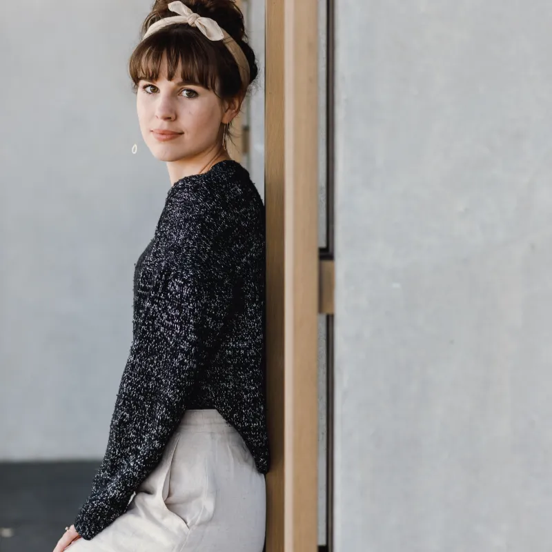 Young woman wearing a grey and silver marled, hand knit sweater