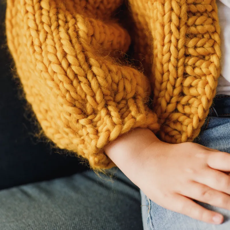 Sleeve on a mustard coloured Mini Love Bomber knitting pattern