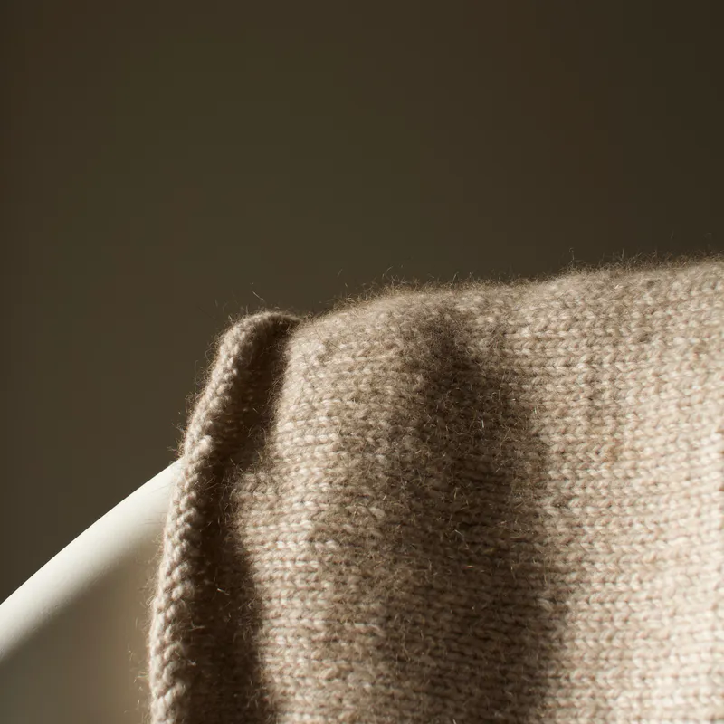 The subtle fuzz of possum merino yarn when it's knit up. The sample is draped over a chair in the late afternoon light.