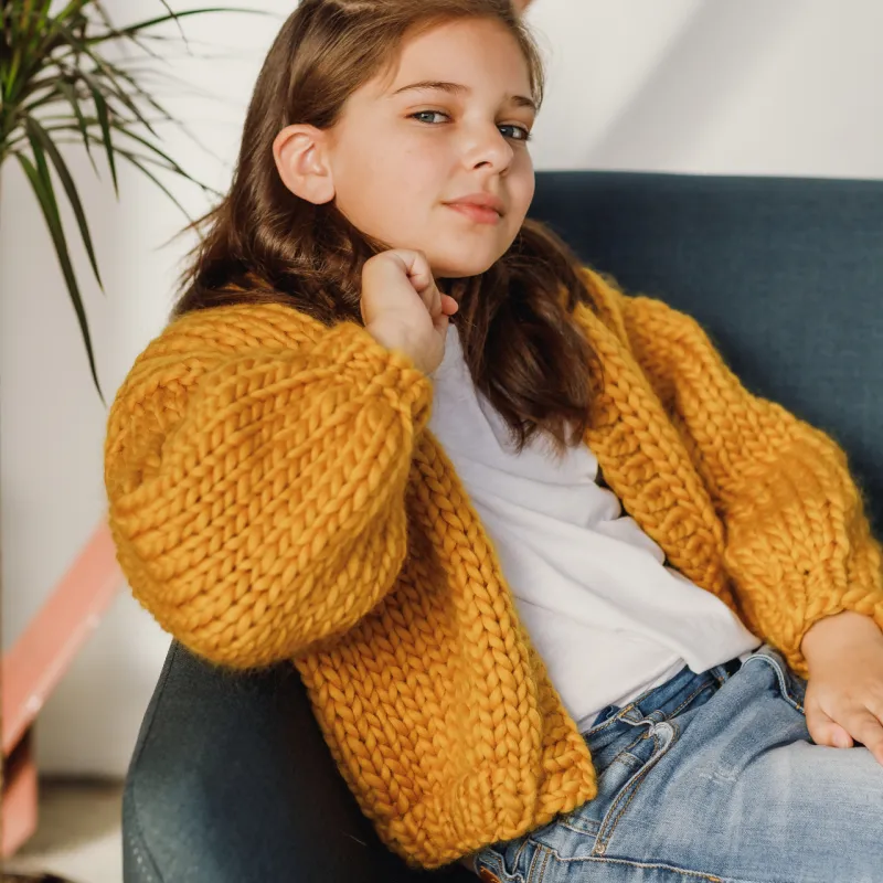Child wearing a mustard Mini Love Bomber knitting pattern