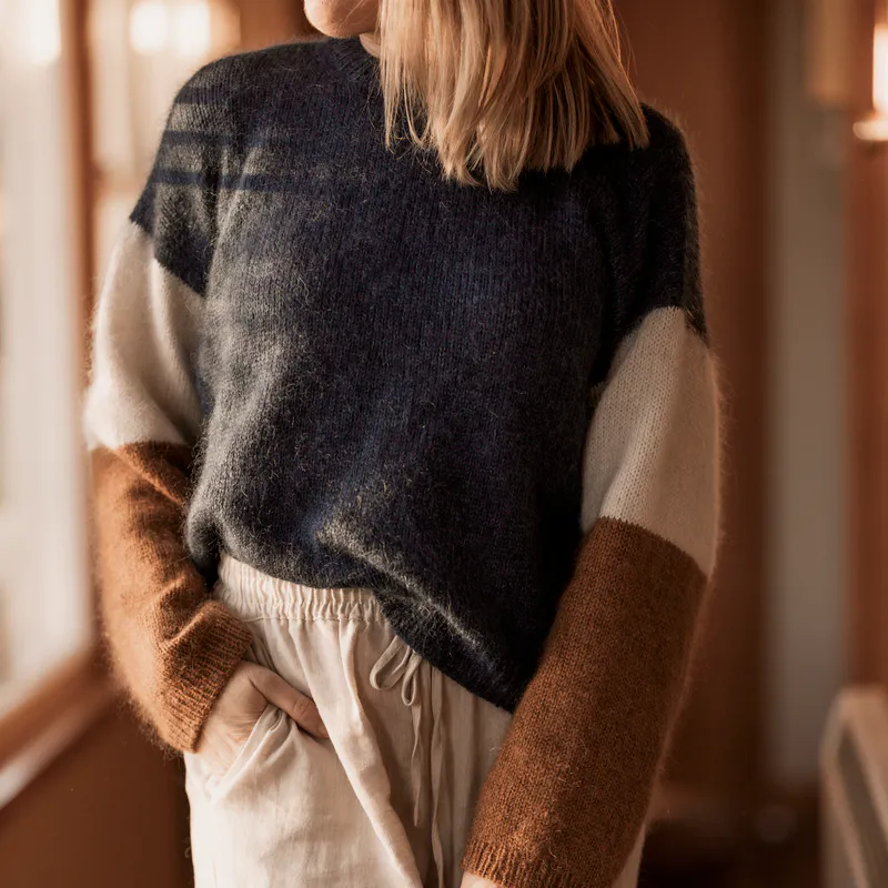 A cropped photo showing the torso of a woman who wears linen pants and a hand knit sweater.