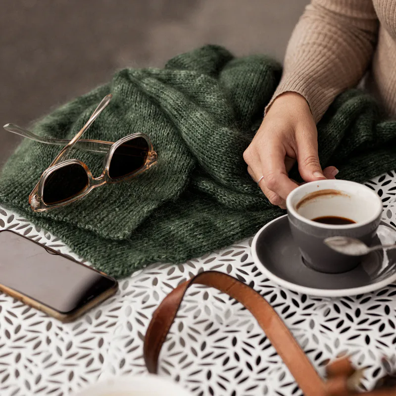 A flatlay of a green hand knit scarf with mohair and sock yarn. The scarf is available as a free knitting pattern