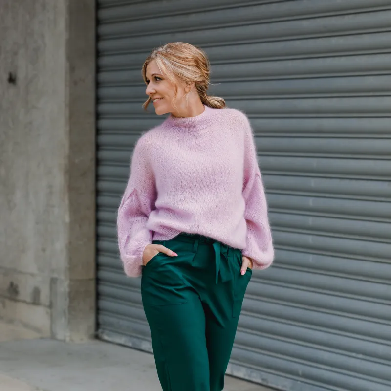 Woman wearing a candy pink sweater with emerald green pants. The sweater is mohair and has been hand knit use a PDF pattern.