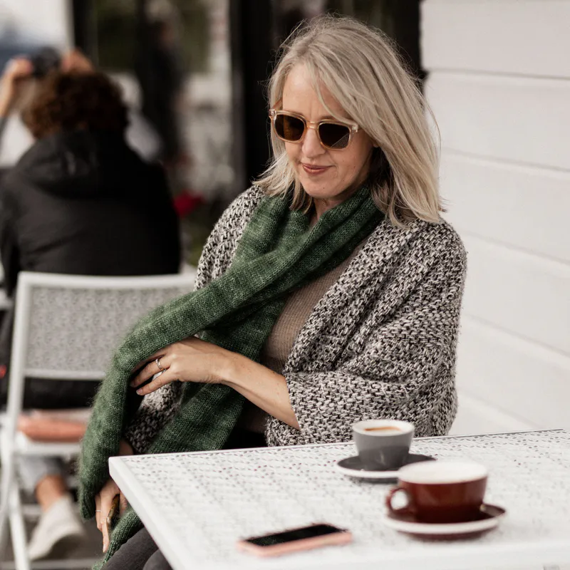 A cosy green, hand knit scarf with a black and white coat for winter