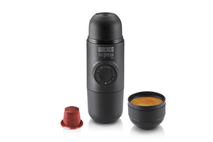 minipresso ns in black is displayed with a nespresso compatible capsule that is upside down and a freshly brewed cup of espresso in front