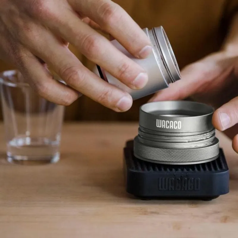 Filling the Picopresso with coffee grinds from the base of a hand operated coffee grinder