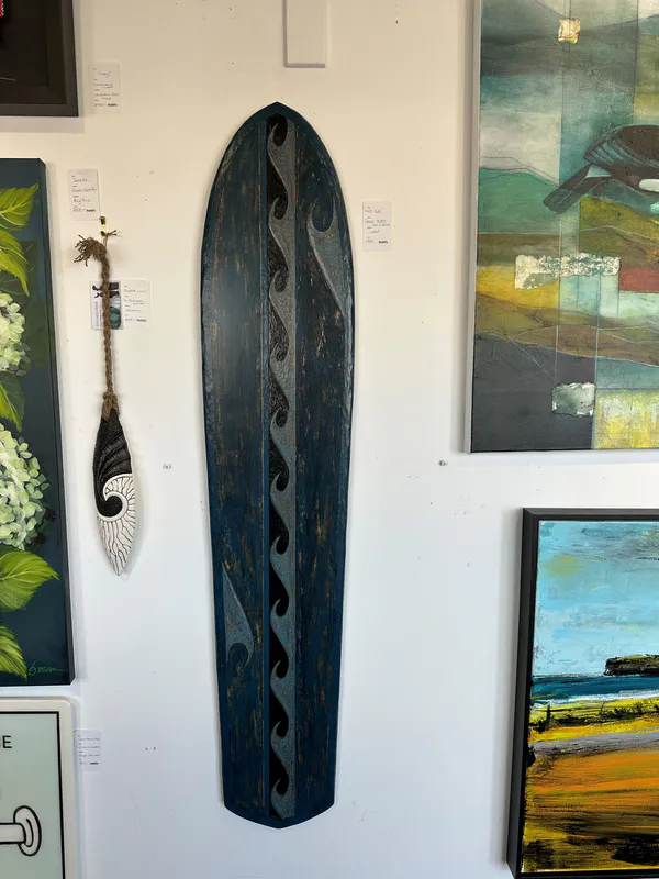 A wooden hand carved sculpture board with wave patterns by New Zealand artist James Atutahi, available at The Little Gallery Tairua