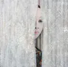 A contemporary painting of a lady looking through sheer curtains by New Zealand artist Hayley Hamilton, available at The Little Gallery Tairua