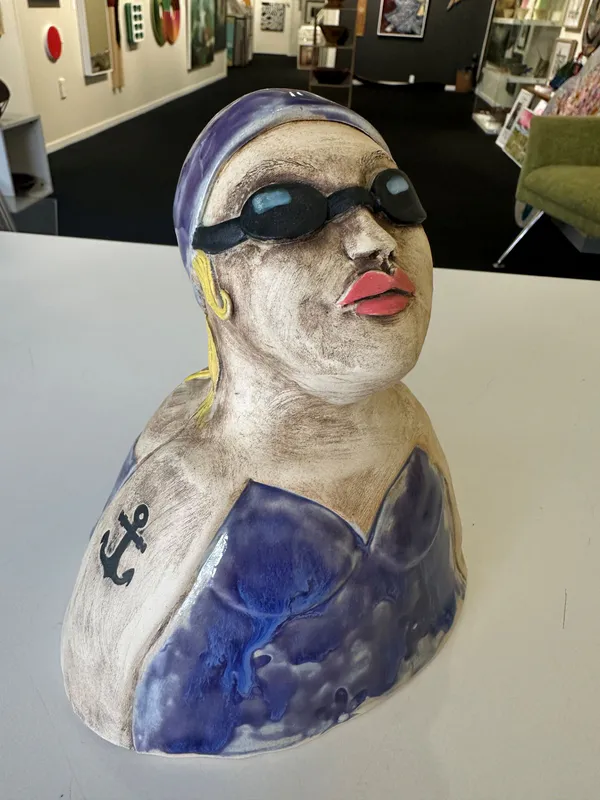 A playful Ceramic sculpture of a swimmer with a cap and tattoo on arm by Nikky Seales, available at The Little Gallery Whangamatā