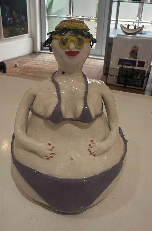An original quirky ceramic figure of a lady in a purple bikini by LeeBee, available at The Little Gallery Whangamatā