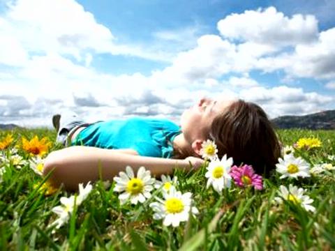 Figure lying in a field covered in wildflowers, looking stress-free and relaxed