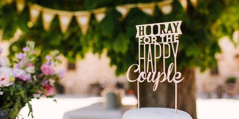 Bunting hanging over table with white tablecloth and flowers and a wedding cake with the message: Hooray for the happy couple!